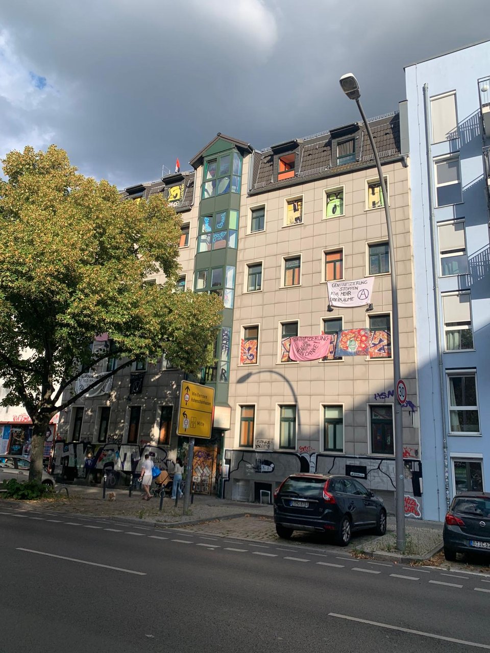 Straßenansicht des Hugohauses mit Transparenten „Gentrifizierung stoppen“ und „Gentrifizierung nein danke“.