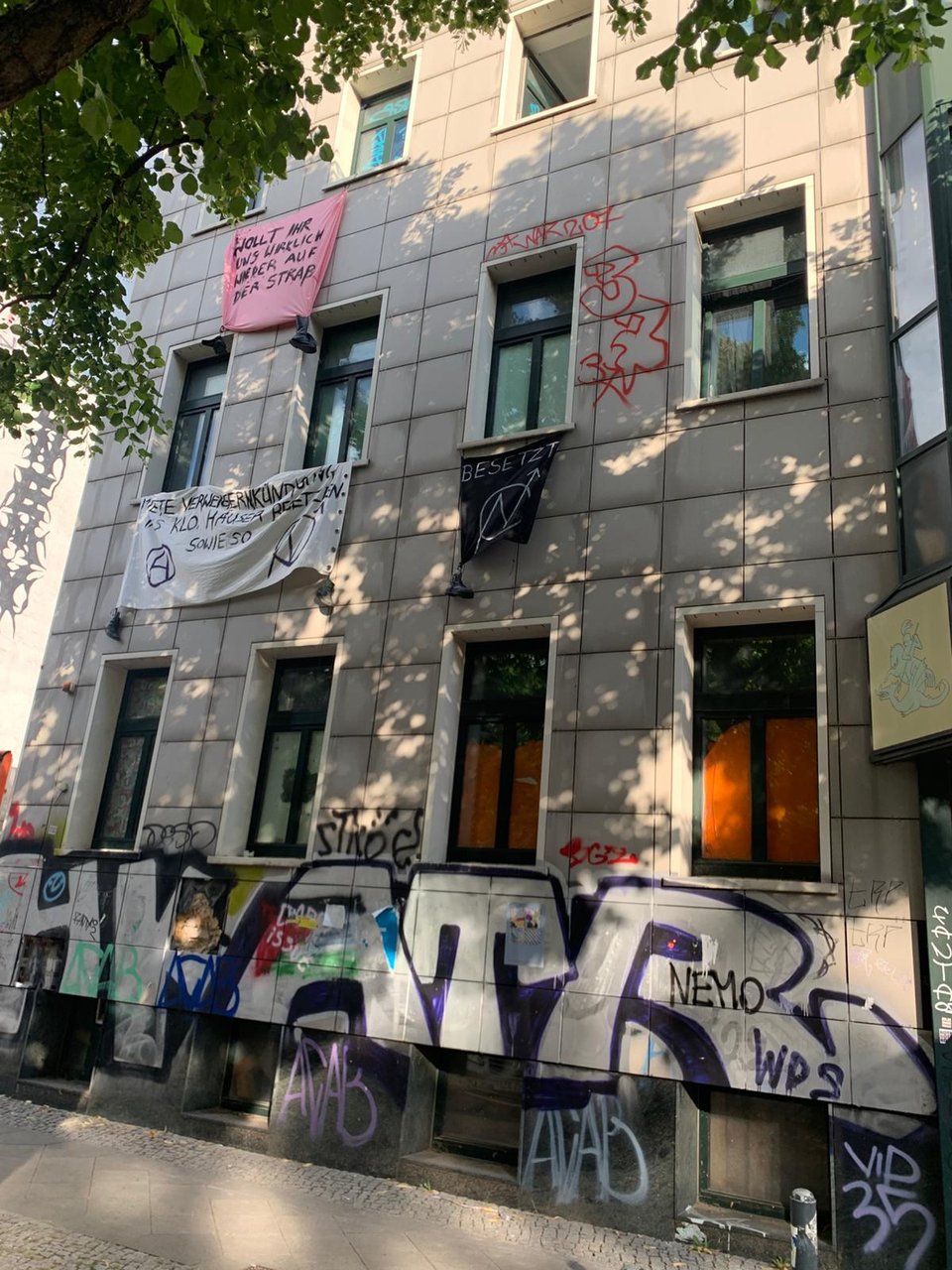 Fassade des Hugohauses mit Transparenten, darunter „Wollt ihr uns wirklich wieder auf der Straße?“ und „Besetzt“.